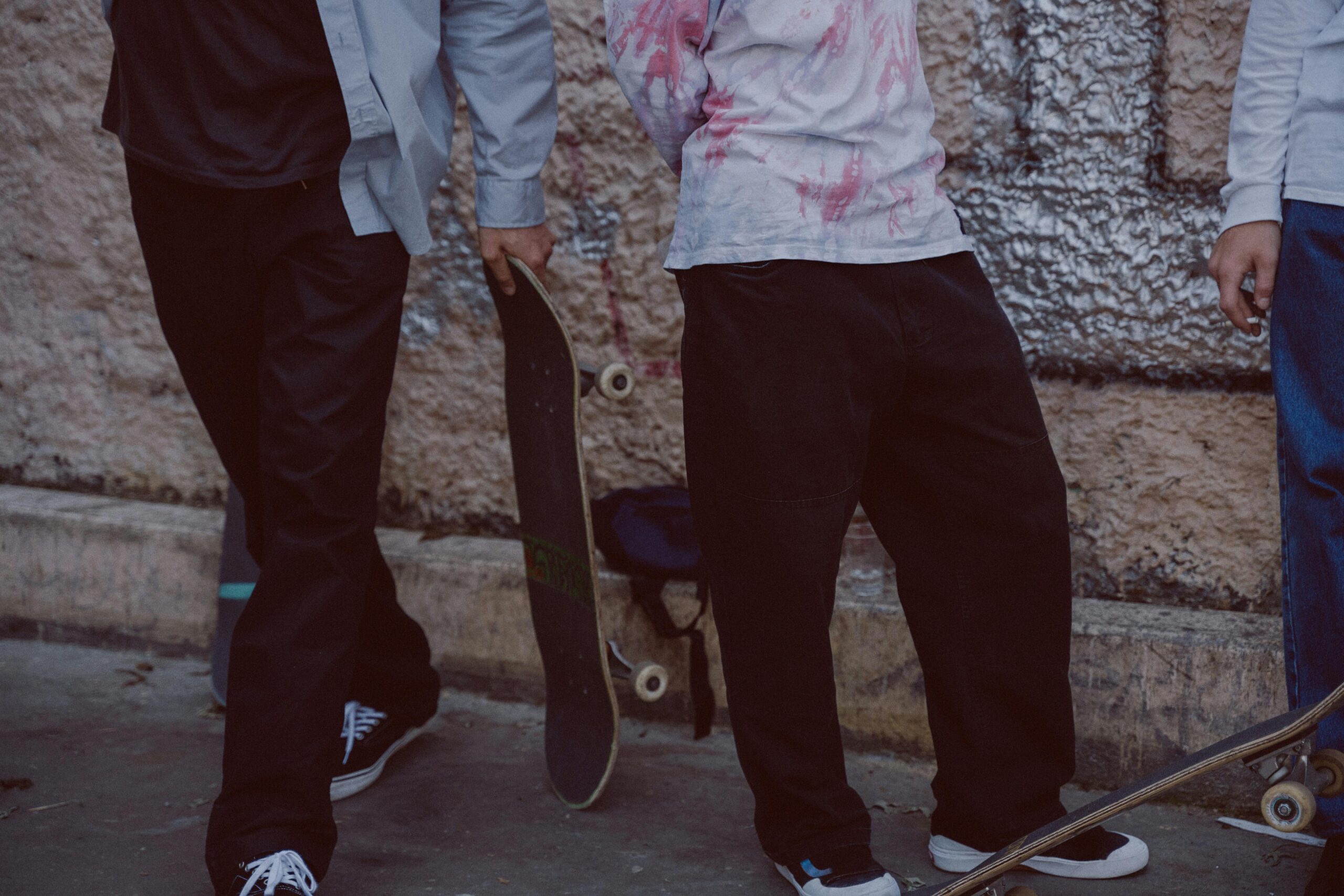 Person In Der Blauen Hose Und Im Rosa Hemd, Die Schwarzes Skateboard Halten